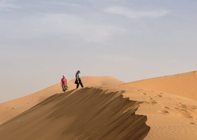 deux personnes en haut d'une dune dans le désert