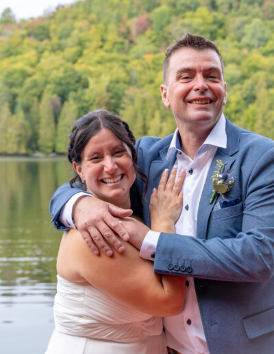 couple de mariés souriant devant un lac