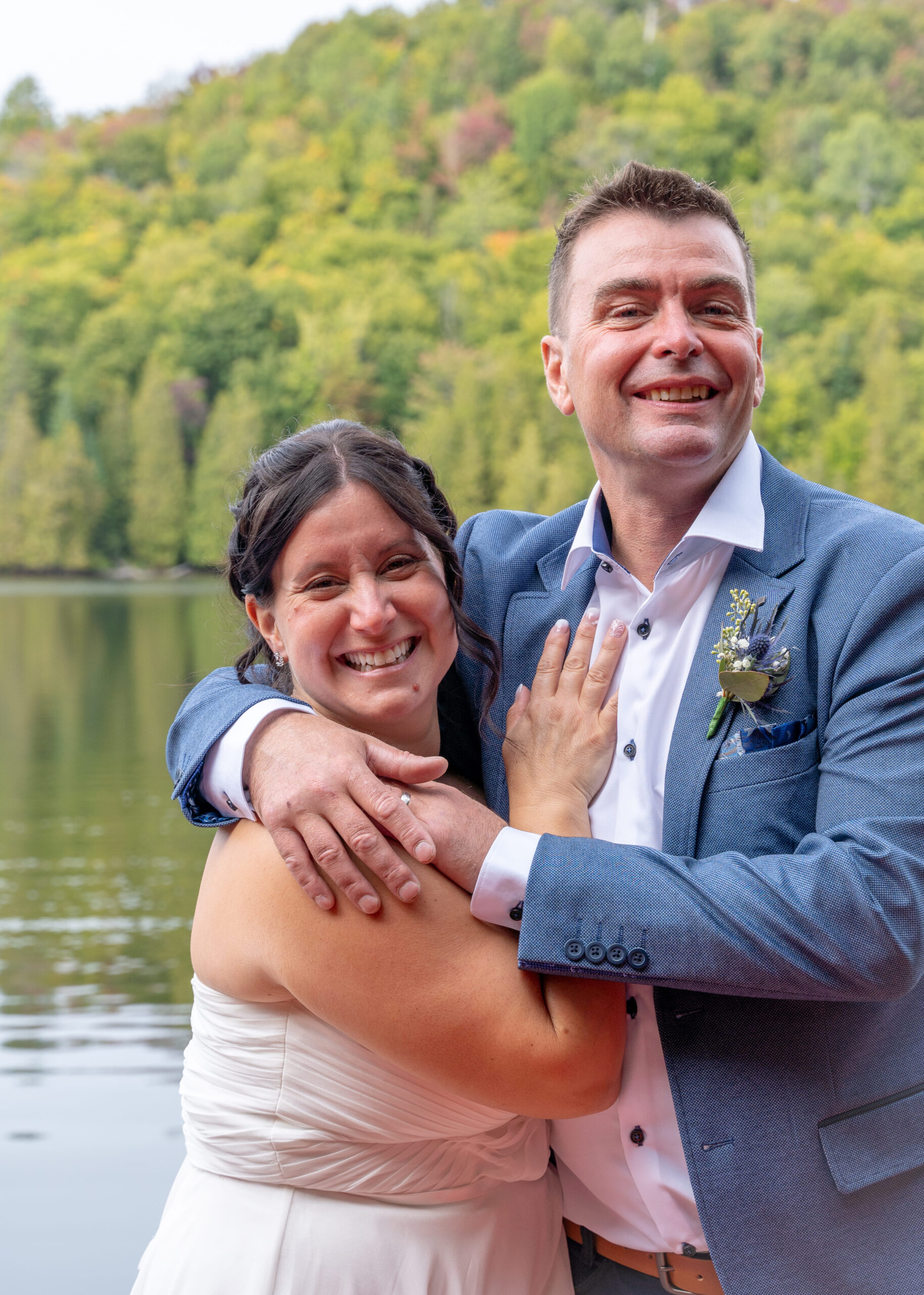 couple de mariés souriant devant un lac