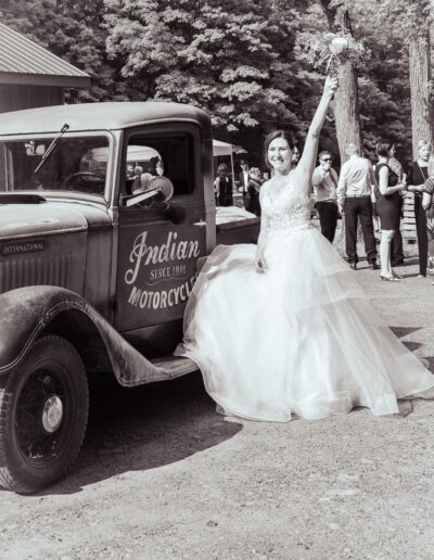 photo noir et blanc mariée à côté d'une veille voiture
