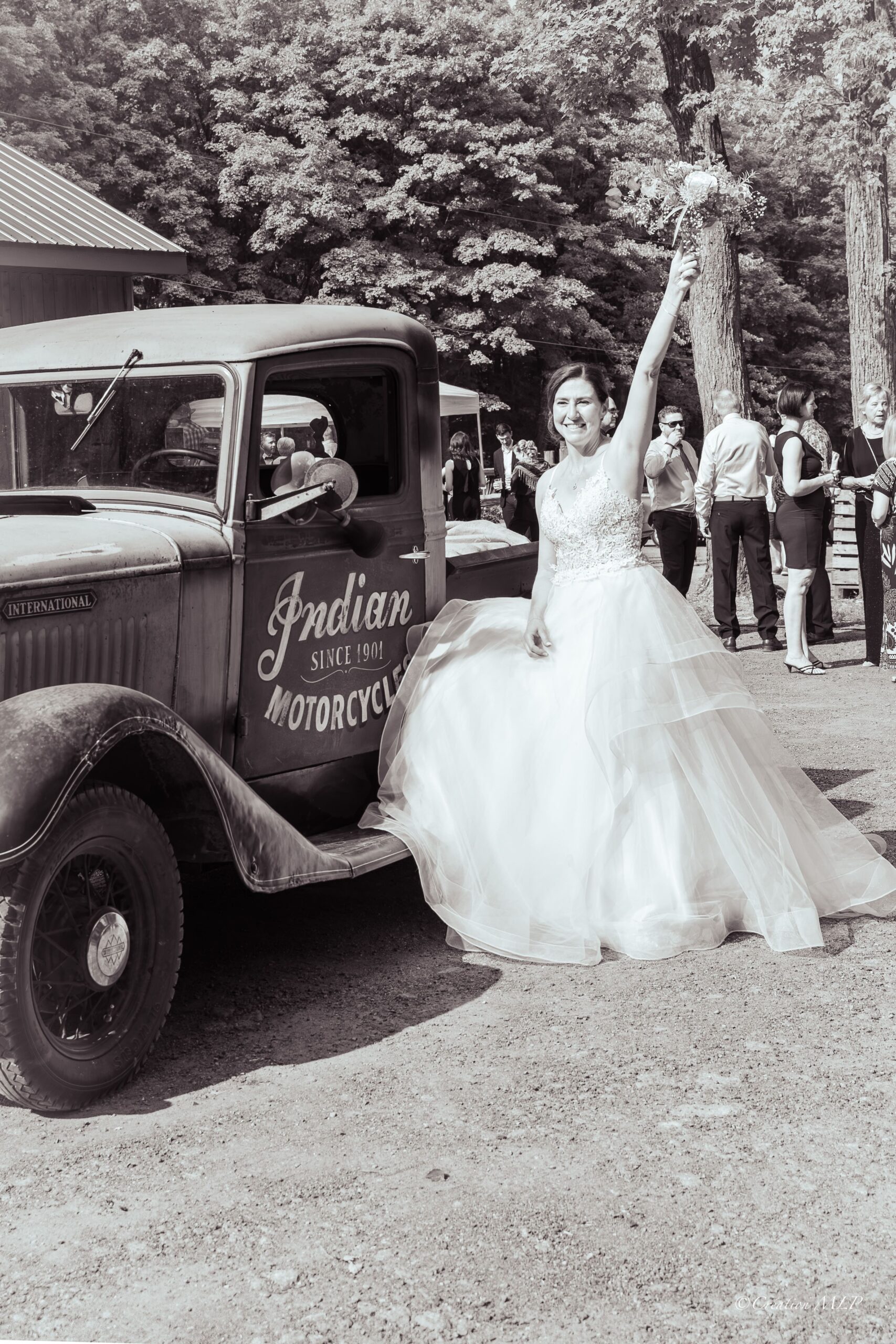 photo noir et blanc mariée à côté d'une veille voiture